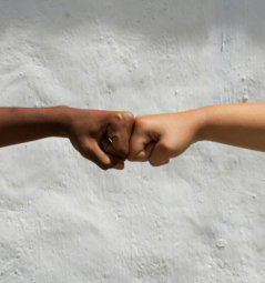 Diverse hands bump fists in solidarity.