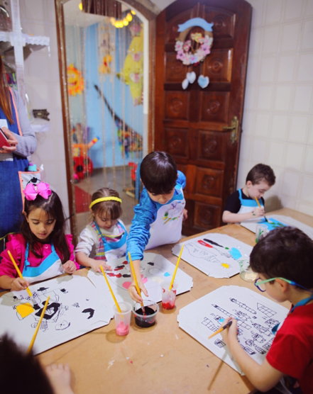 a group of children sitting at a table doing crafts